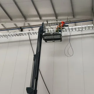Técnico en plataforma elevadora instalando cableado estructurado en el techo de la planta de Agronutrición