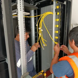 Técnicos de ESVA instalando cableado de fibra óptica en rack de comunicaciones, proyecto Agronutrición